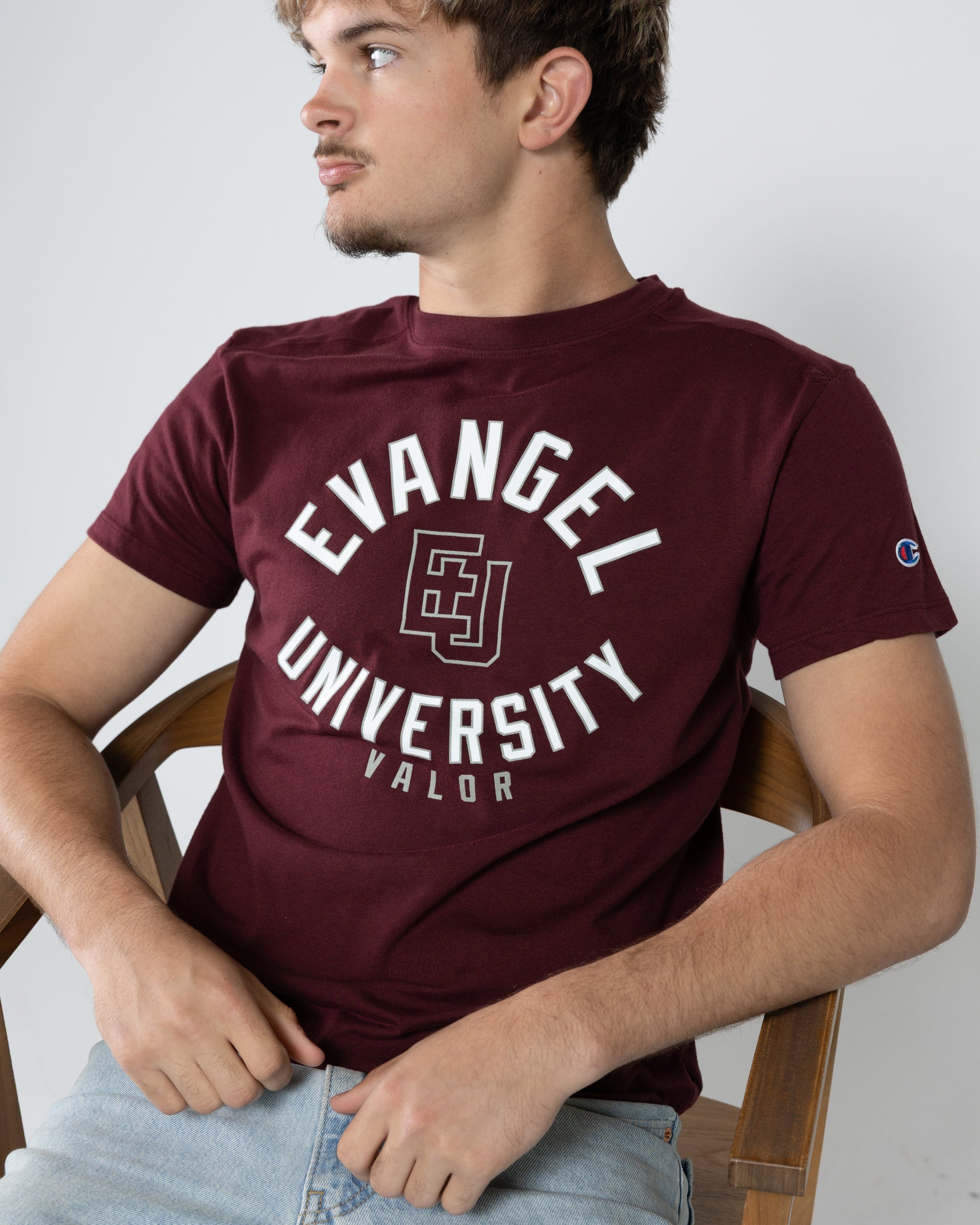 Person wearing a maroon 'Evangel University Valor' t-shirt sitting on a chair.